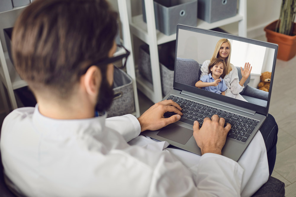 Doctor consults a woman with a child using a computer web camera in the office of a medical clinic.